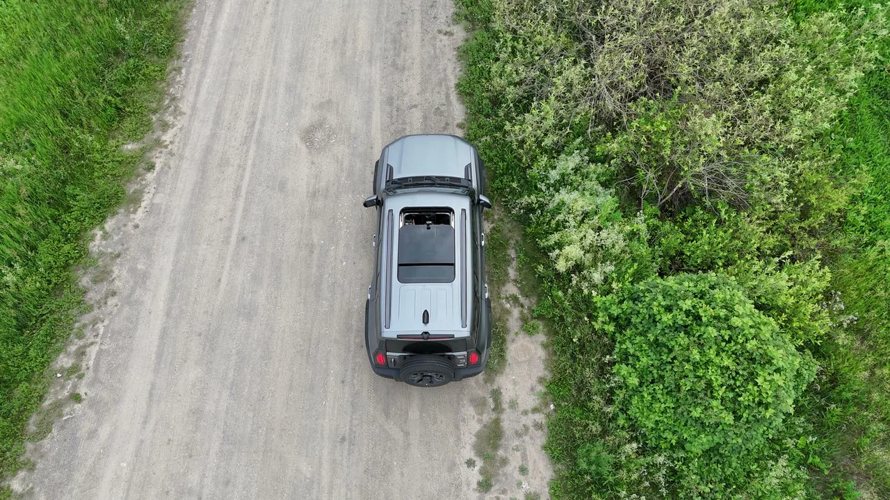 Jetour T2 сверху на грунтовой дороге среди зелени